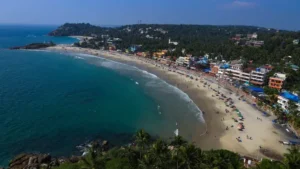 A stunning aerial view of a Kerala beach with colorful buildings, palm trees, and clear blue waters, perfect for Kerala tour packages